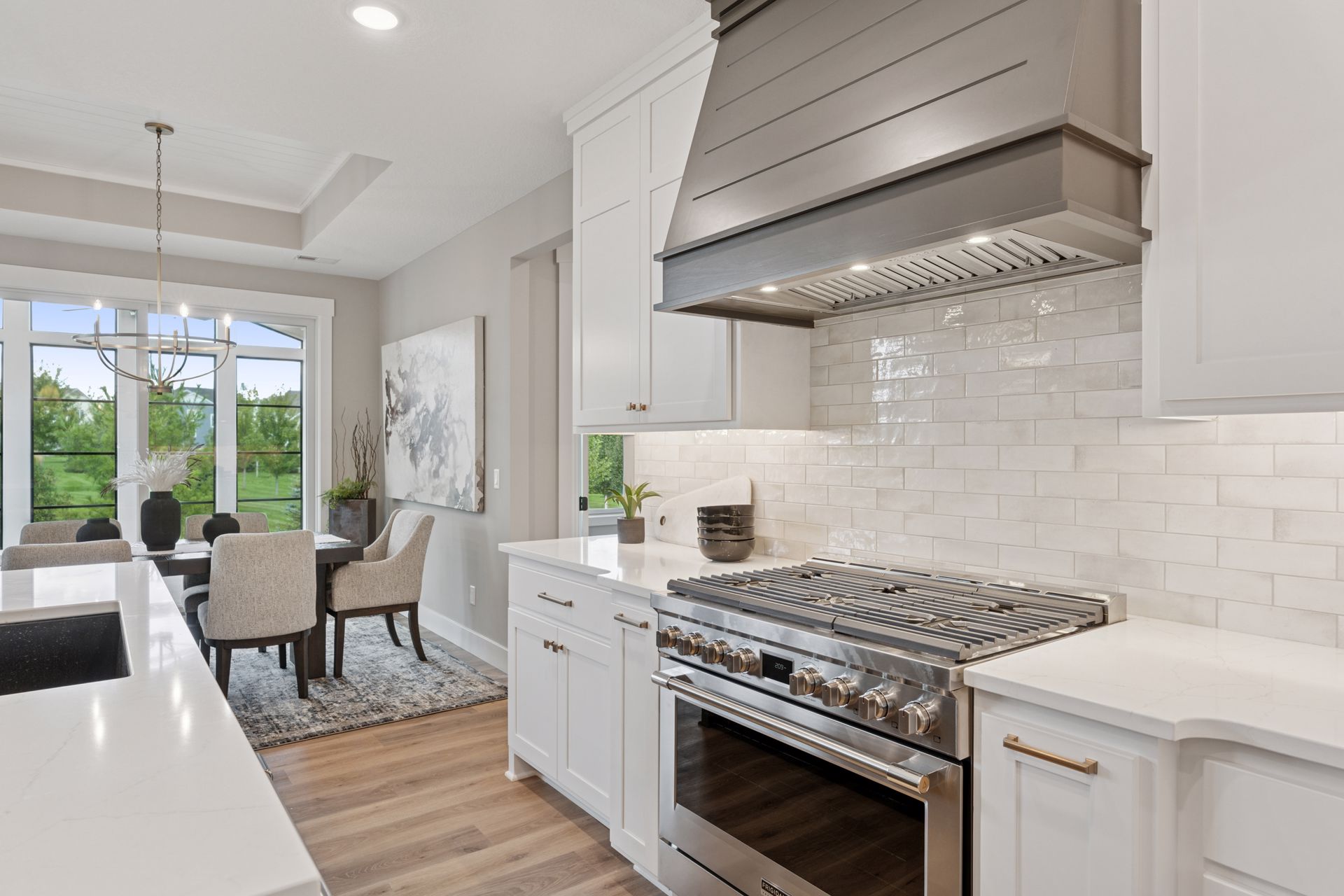 Luxury kitchen featuring stainless steel range, hood, and subway tile backsplash