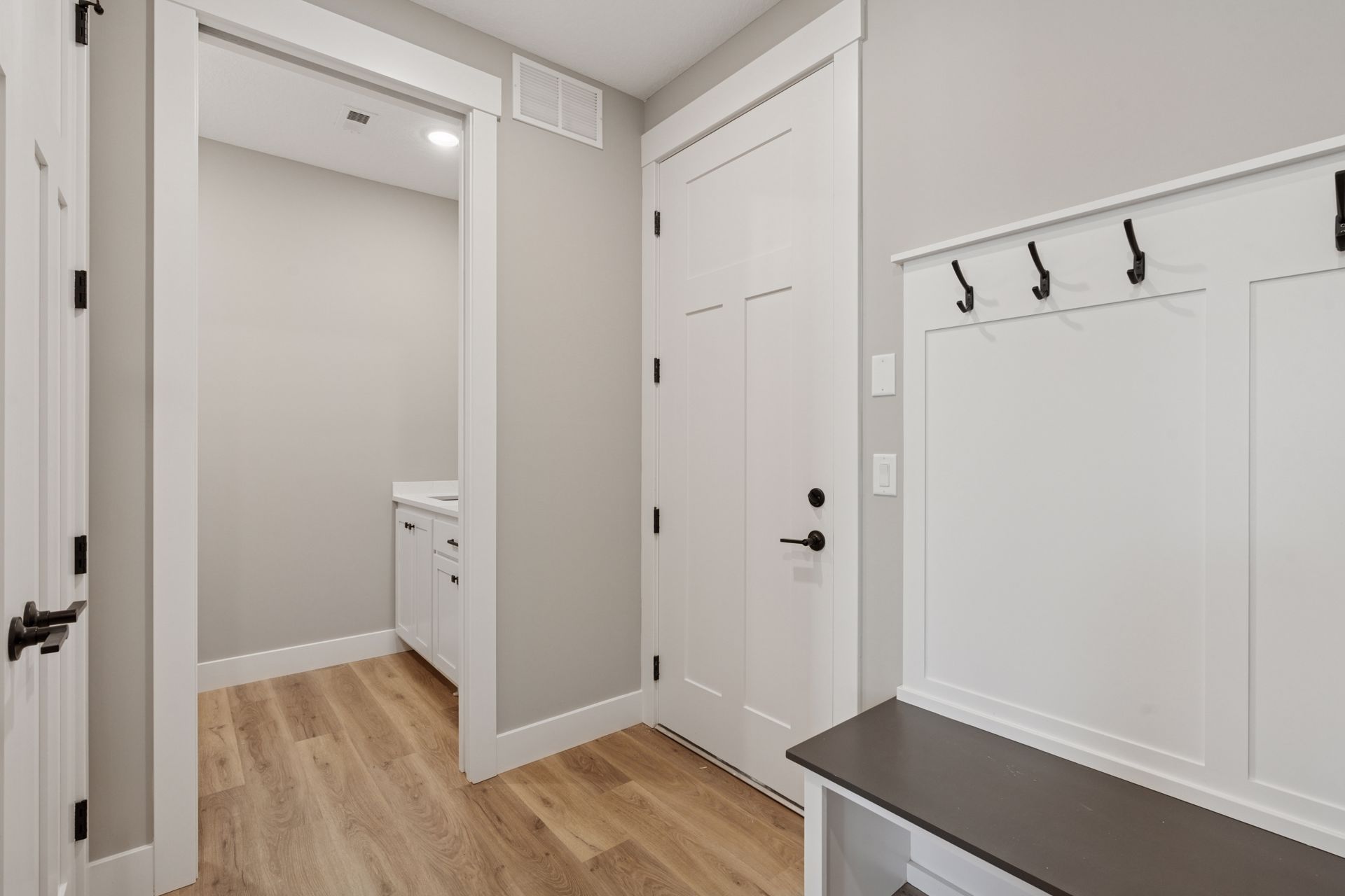 Functional mudroom featuring bench, coat rack, and access to laundry