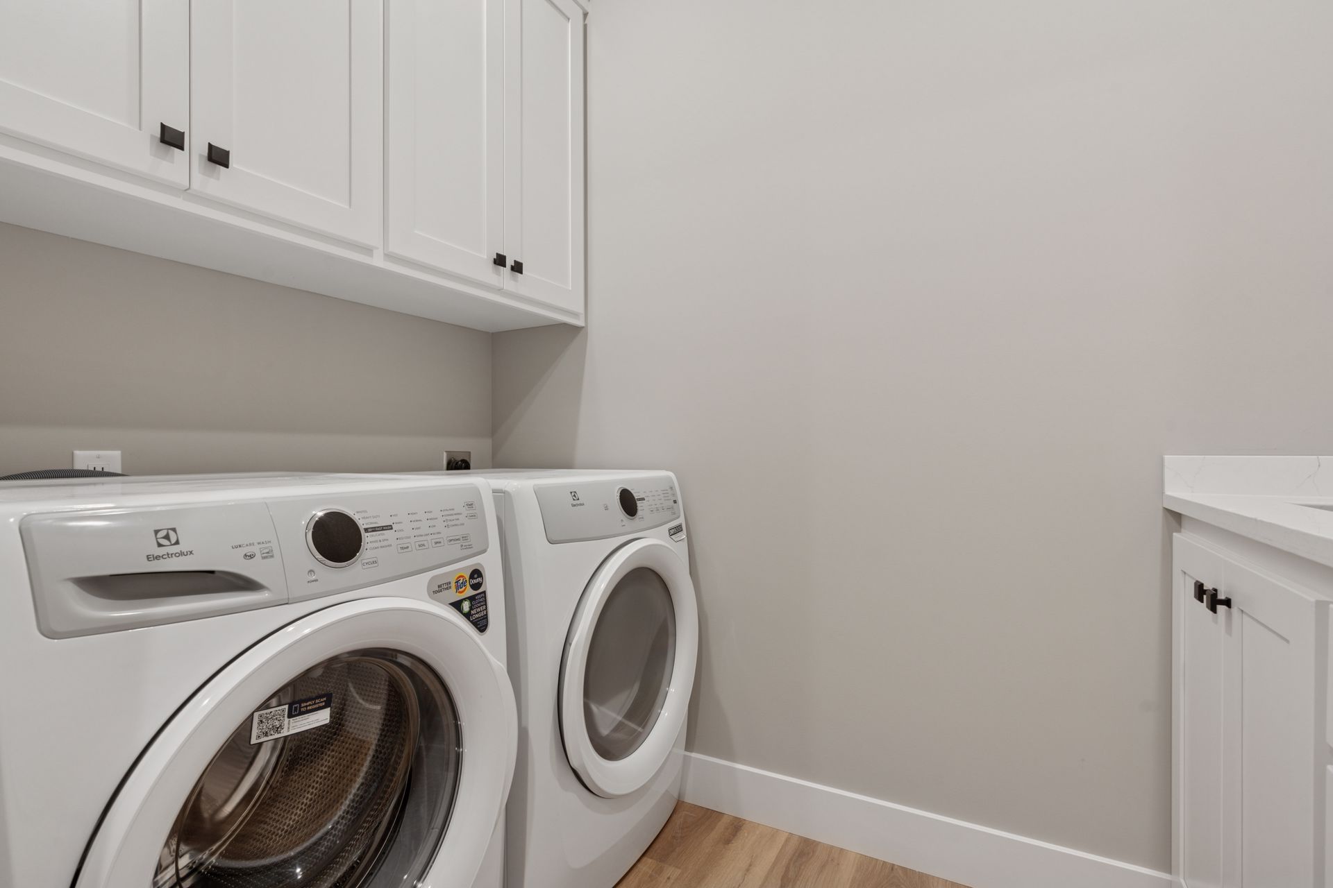 Modern laundry room featuring washer, dryer, cabinetry, and utility sink