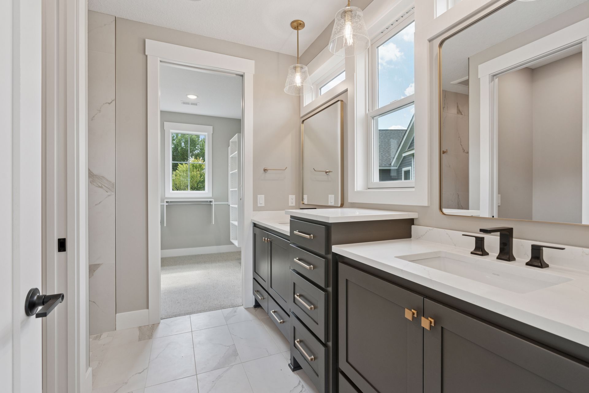 Luxury owner’s bathroom featuring double vanities and natural light window