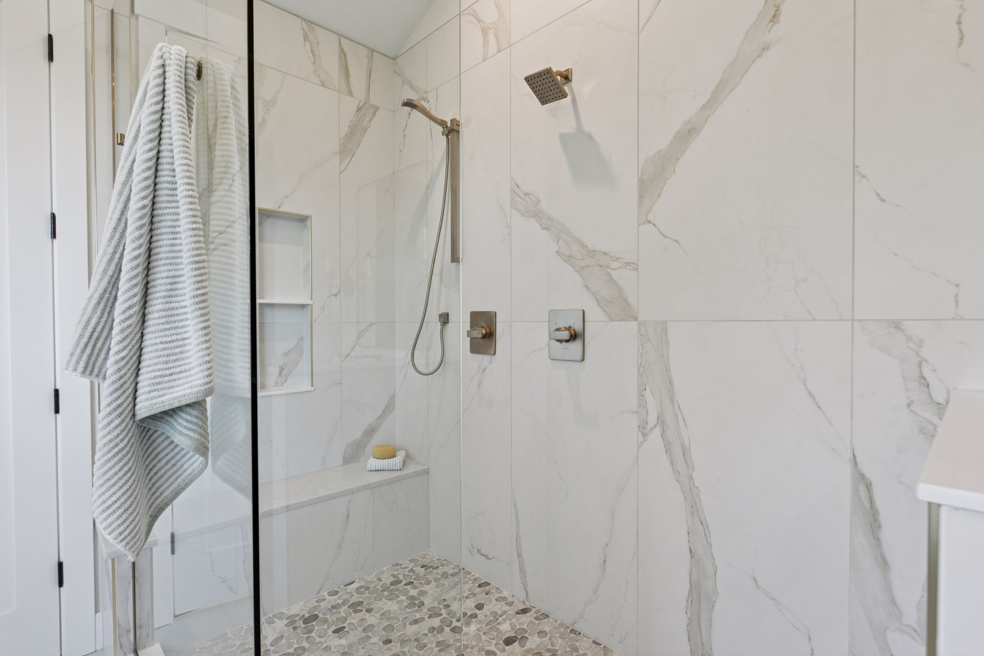 Spacious spa shower with rainfall shower head, built-in bench, and recessed niche