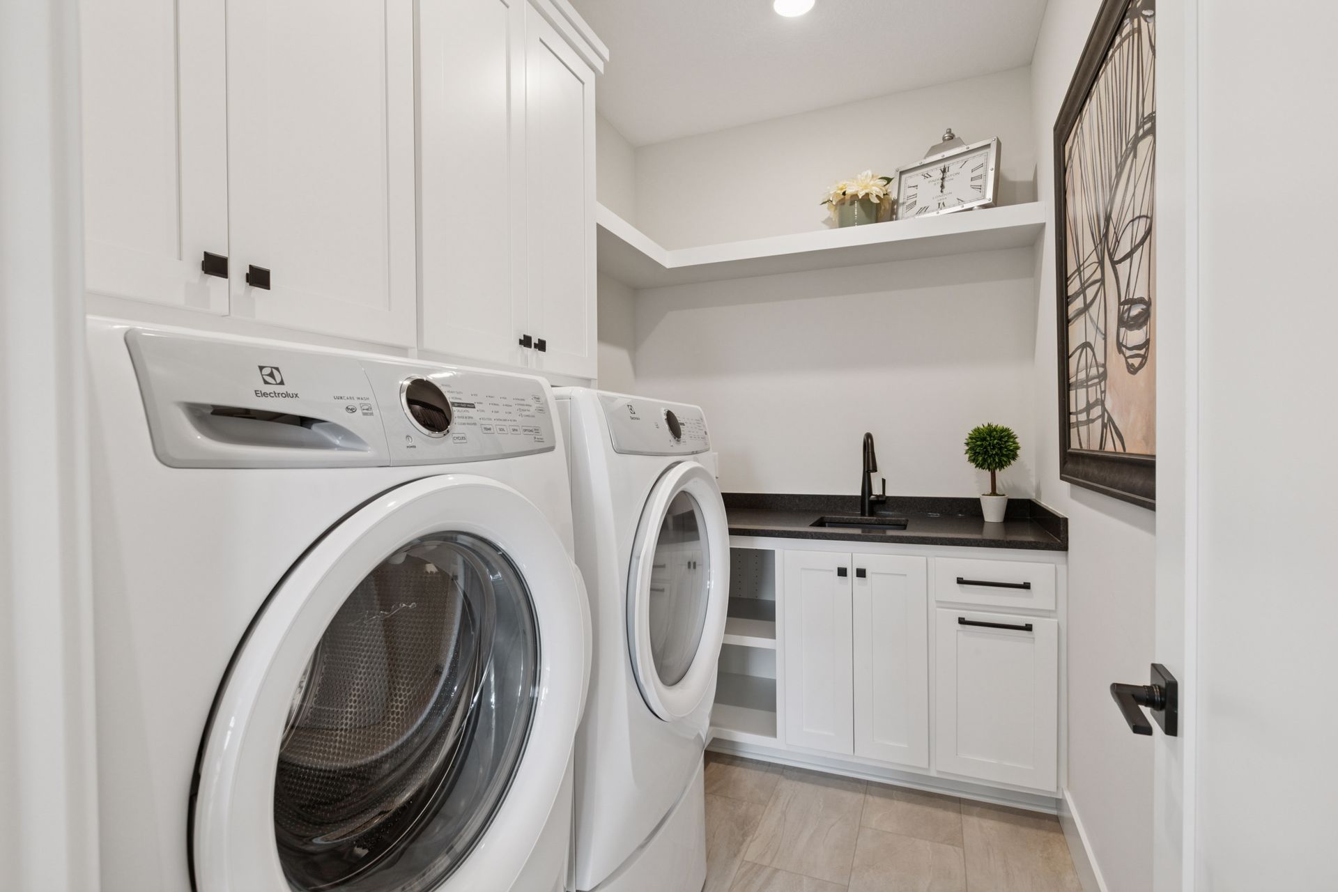 Laundry room with high-end built-in washer and dryer, cabinets, and utility sink